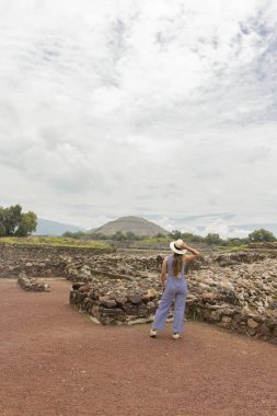 Şirin bir şapkayla yürüyen ve Meksika 'daki Teotihuacan piramitlerini gören genç bir Latin.