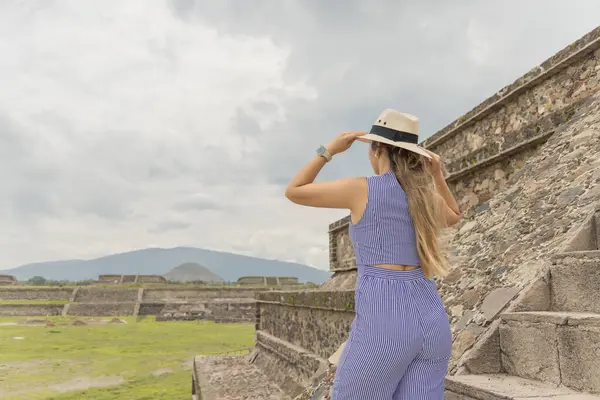 Turist kadın şirin şapkasıyla Teotihuacan piramitlerinden birine tırmanıyor.