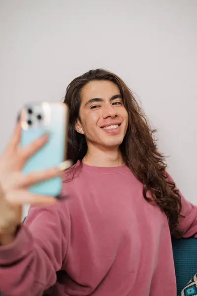 Dışarda cep telefonuyla selfie çekerken gülen ikili olmayan kişi eğleniyor..
