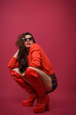 İkili olmayan kişi kırmızı bir stüdyoda poz veriyor. Adamın sanatsal bir ifadesi var. İkili olmayan insanlar kavramı. gurur