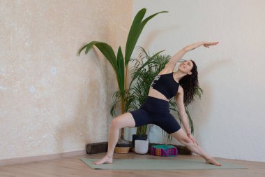 Sevimli genç Latin kadın kolları havada yoga yapıyor.