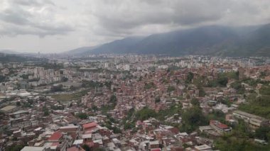 Günbatımında Venezuela ve Latin Amerika 'nın en büyük gecekondu mahallesi olan Petare Mahallesi ile Avila Dağı' nın arka planında hava manzarası.