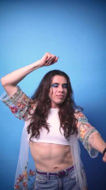 Mavi arka planda uzun saçları olan ve uzayı kopyalayan mutlu ve ışıl ışıl, ikili olmayan bir stil sahibi.