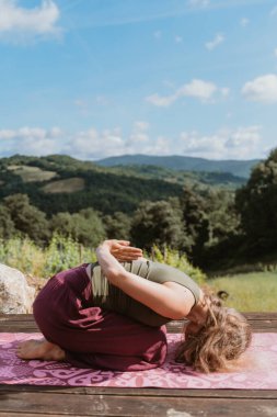 Yoga yapan genç bir kadın tepe manzarasına karşı. Doğa arka planında sabah rahatlama kavramı