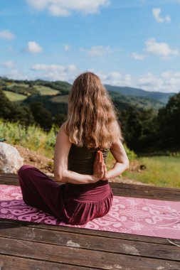 Yoga yapan genç bir kadın tepe manzarasına karşı. Doğa arka planında sabah rahatlama kavramı