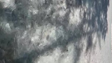 Yukarıdan akan temiz dağ suyu manzarası, doğa ve çevre. Temiz su sığ bir nehirde akar. Su akışının desenli ve soyut bir dokusu var..