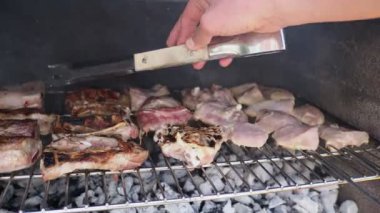 Bahçe barbeküsünde kömürde farklı türde et pişiren bir adamın elleri. Yemek, insan ve aile zamanı kavramı