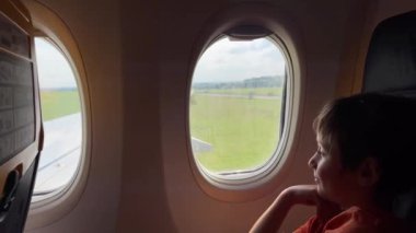 Küçük gezgin uçağın kalkışı sırasında pencereden dışarı bakıyor.