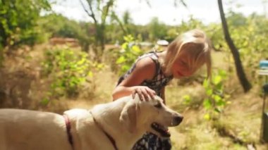 Küçük kız sahibini bekleyen bir köpekle konuşur, onu sakinleştirir.