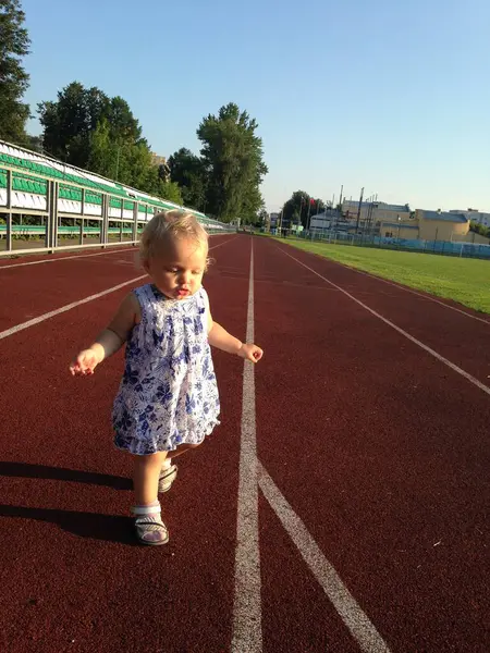 Stadyum koşu bandında koşan komik küçük kız. Sağlıklı yaşam tarzı. Çocuklar açık hava aktivitesi