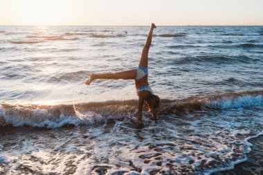 Genç bir kız dalgalarda takla atıyor, enerjisi bu neşeli anda yakalanıyor..