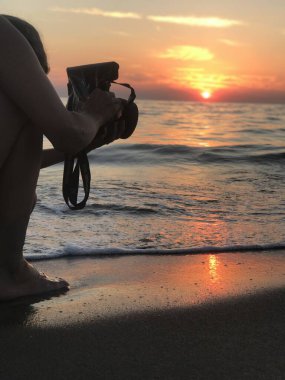 Bir fotoğrafçı suda batan güneşin son ışınlarını yakalar.