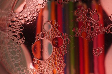 Suda asılı duran yağ damlacıklarının soyut makro fotoğrafçılığı büyüleyici bir kabarcık deseni yaratıyor. Kırmızı, mavi ve sarının canlı arkaplanı kırılmayı ve dokusunu arttırarak eşsiz ve renkli bir kompozisyon oluşturur.