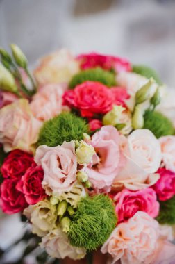 Pembe, kırmızı ve beyaz güllerin bulunduğu yemyeşil aksanlı renkli bir buketin yakın plan görüntüsü. Çiçek aranjmanları, düğün tasarımı ve mevsimlik dekorasyon için ideal.