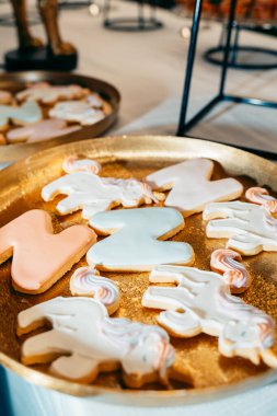 Tek boynuzlu at ve harf şeklinde kurabiyeler. Pastel kremayla süslenmiş, altın tepside dizilmiş. Doğum günleri, çocuk partileri ya da özel durumlar için mükemmel.