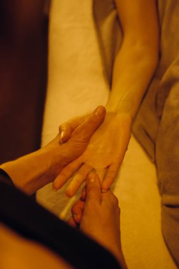 Bir el masajı seansının kapanışı terapistin müşterinin eline nazikçe baskı uyguladığı bir seans. Sahne rahatlamayı, sağlığı ve masaj terapisinin iyileştirici faydalarını teşvik ediyor..