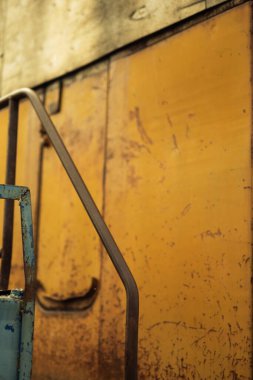 A close-up shot of a rusting yellow train step highlights peeling paint and corroded metal clipart