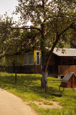 Countryside house with green and yellow walls surrounded by trees clipart