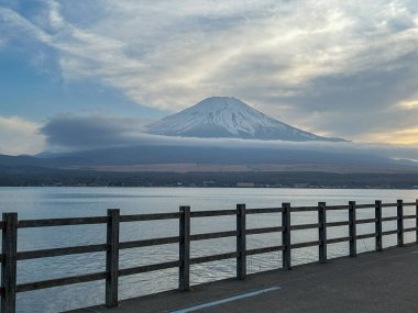 Fuji Dağı göl kenarındaki ahşap korkuluklara bakıyor.