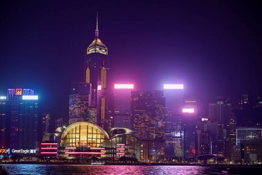 Night view of skyscrapers with colourful lights reflecting on the water at Victoria Harbour. This photo was taken in Tsim Sha Tsui, Hong Kong on November 26, 2023.