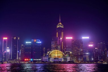 Night view of skyscrapers with colourful lights reflecting on the water at Victoria Harbour. This photo was taken in Tsim Sha Tsui, Hong Kong on November 26, 2023.