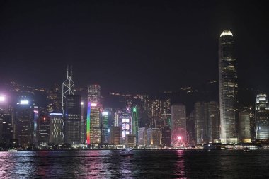 Night view of skyscrapers with colourful lights reflecting on the water at Victoria Harbour. This photo was taken in Tsim Sha Tsui, Hong Kong on November 26, 2023.