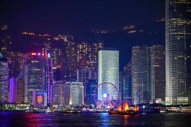 Night view of skyscrapers with colourful lights reflecting on the water at Victoria Harbour. This photo was taken in Tsim Sha Tsui, Hong Kong on November 26, 2023.