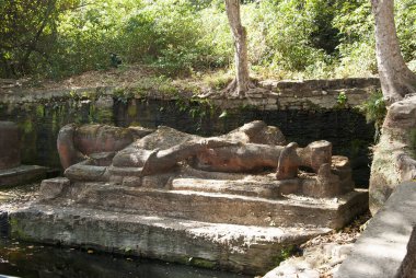 shesha shayana, sleeping vishnu sculpture inside bhandavgarh tiger reserve during a wildlife safari on a hot summer day clipart