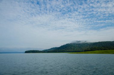 Bhadra nehrinin durgun sularında Bhadra kaplanı koruma alanı içinde vahşi yaşam safarisi sırasında, dağları ve bhadra ormanlarını kaplayan güzel bir sis manzarası.