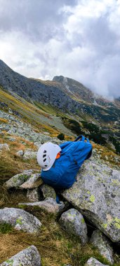 Seyahat için sırt çantası, dağlara tırmanmak için kask. Dağlarda geziyorum. High Tatras 'ta yürüyüş. Bir yaşam tarzı olarak dağlarda yürüyüş yapmak. Dağ tırmanma ekipmanı. Dağ yolunda dur. Dikey fotoğraf