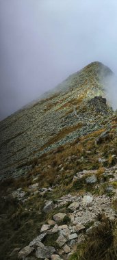 Favori bir hobi olarak dağlarda yürüyüş yapmak. Aktif yaşam tarzı. Yürüyüş patikalarından Tatra Dağları ve Yüksek Tatralar 'ın manzarası. Dağlar arasındaki dağ tepeleri, yamaçlar ve vadiler. Posrednia Turnia Bulutlarda