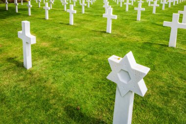 Beyaz haç sıraları ve Davut Yıldızı Fransa 'nın Normandiya kentindeki Amerikan askeri mezarlığında mezarları işaretliyor. Kutsanmış anıların yeri.