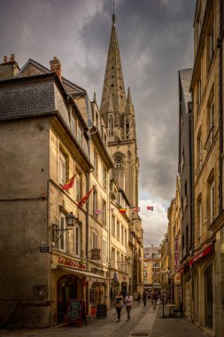 Fransa 'nın Normandiya şehrinde yer alan yüksek Saint Sauveur Kilisesi' nin yer aldığı Caen 'in tuhaf sokak manzarası. Yayaların ve yerel işletmelerin bulunduğu manzaralı kentsel atmosfer.