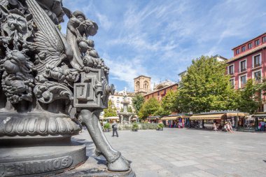 Plaza de Bib Rambla 'da işlenmiş bir demir lamba direğindeki mitolojik figürler ve arka planda Granada, İspanya' daki Katedral..