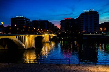 Guadalquivir Nehri ve San Telmo Köprüsü, arka planda Plaza de Cuba 'nın modern binaları olan Seville, İspanya' da alacakaranlıkta aydınlandı..