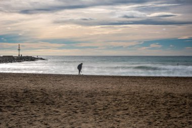 Bulutlu bir kış gününde Playa del Zapillo 'da denizin kenarında duran yalnız bir şahsiyet, Almerya, Endülüs, İspanya.