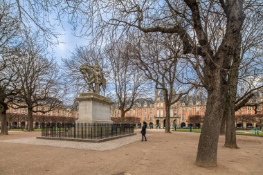 Statue of Luis XIII in Place des Vosges, Paris, France, amidst lush trees. clipart