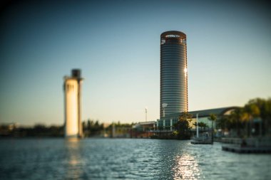 Torre Sevilla gökdeleni (sağda) ve Schindler toer (solda, odak dışı) Guadalquivir nehrinin kıyısında, Seville, İspanya. Objektifin odak düzlemini eğerek sığ alan derinliğine ulaşıldı.