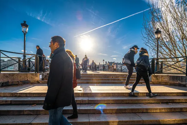 stock image Couples and individuals enjoying the iconic Pont des Arts bridge in Paris under a clear sky.