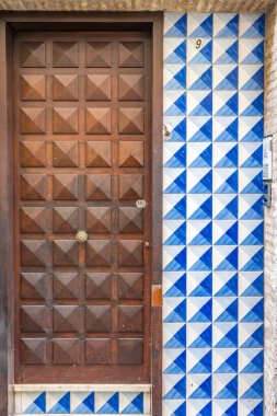 1970 'lerden kalma, Seville, İspanya' da bulunan mavi geometrik fayansları olan eski bir ahşap kapı. Tarihi ve kültürel mimariyi yansıtıyor.