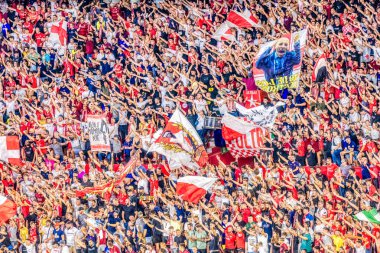 Sevilla FC taraftarlarının coşkulu kalabalığı bayrak sallıyor ve maç boyunca kutlama yapıyorlar..