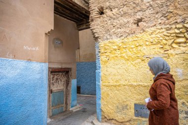 Bir kadın geleneksel kıyafetleriyle Fez Medine 'de eski bir sokakta dolaşıyor..