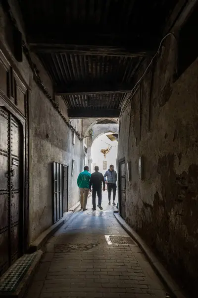 stock image Young men walking down a narrow alleyway in the maze-like streets of the Fez Medina, Morocco.