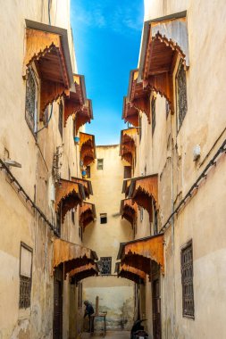 Fez Medina 'da süslü ahşap güneşlikleri olan dar bir sokak..
