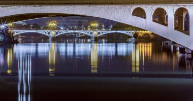 Uzun pozlama, San Telmo Köprüsü 'nü ön planda ve Triana Köprüsü' nü alacakaranlıkta aydınlattı..