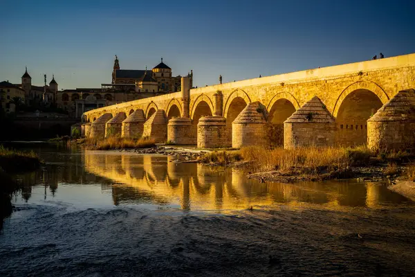Roma 'nın Cordoba Köprüsü, Guadalquivir Nehri' ne yansıyan altın günbatımı ışığıyla yıkanır..