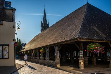 Questembert, Brittany, Fransa 'daki tarihi Les Halles pazarının günbatımı manzarası. İçinde kaldırım taşı sokaklar, gölgeler ve kilise kulesinin silueti var..