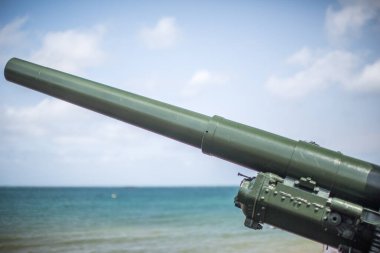 Gold Beach, Arromanches, Normandiya, Fransa 'da kıyı şeridi ve okyanus manzaralı tarihi bir askeri topun yakın çekimi..