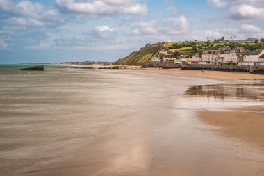 Arromanches, Normandiya, Fransa 'daki Gold Beach' te bulunan tarihi Dut B 'nin uzun pozlama fotoğrafı. Huzurlu kıyı manzarası ve huzurlu sular bir huzur hissi uyandırıyor..