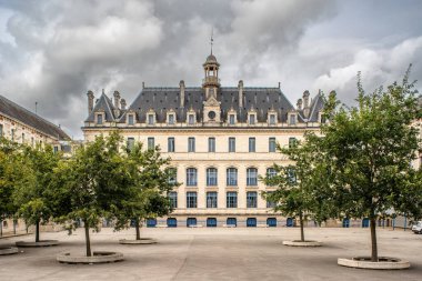 Vannes, Brittany, Fransa 'da bulunan tarihi bir bina. Önünde ağaçlar ve bulutlu bir gökyüzü olan karmaşık mimariyi gözler önüne seriyor..